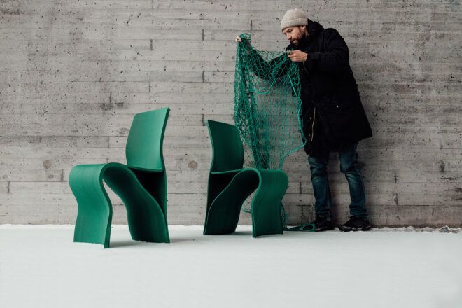 A man holding a green fish net over two green chairs