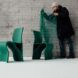 A man holding a green fish net over two green chairs