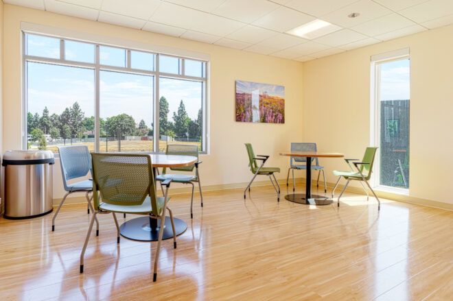 Two tables with four chairs with tall windows looking out to the surrounding campus