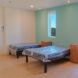 Two single beds with side cabinets against a mint-colored wall. The door to the adjacent bathroom is open