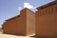 Two red-earth brick buildings with a narrow walkway between