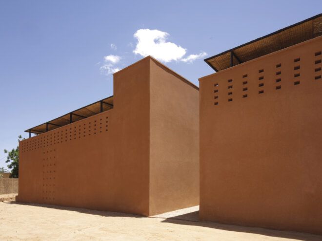 Two red-earth brick buildings with a narrow walkway between