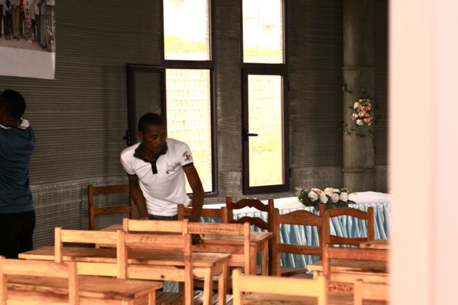 A classroom with a man arranging the chairs