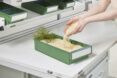 Two hands cupping granules and letting it spill into a green bin