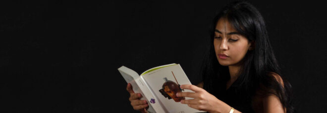 Designer Nuhayr Zein seated on the floor, resting her arms on an ottoman from Leukeather's SEEDS Series, reading a book