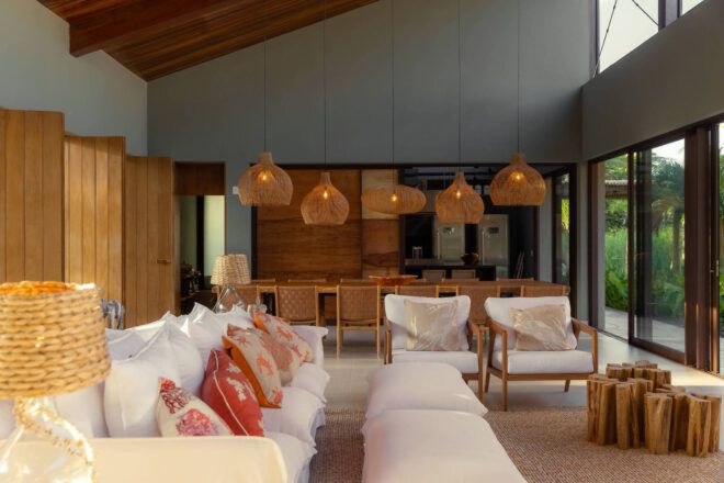 Interior living room area with wooden chandeliers hanging in the background to a white couch and seating area