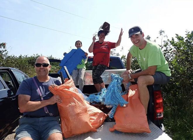 A group of people on a vehicle with bags to collect trash