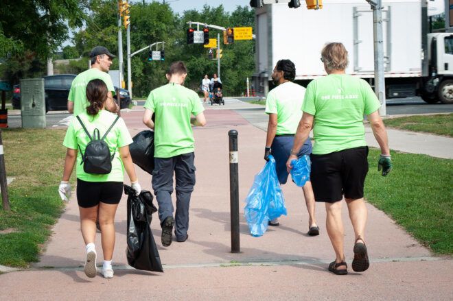 A group of people wearing green shirts and plastic bags to clean up trash