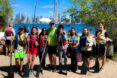 A group of people standing next to each other smiling into the camera with the backdrop of a pier