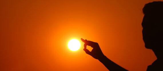 A silhouette of a person touching the sun