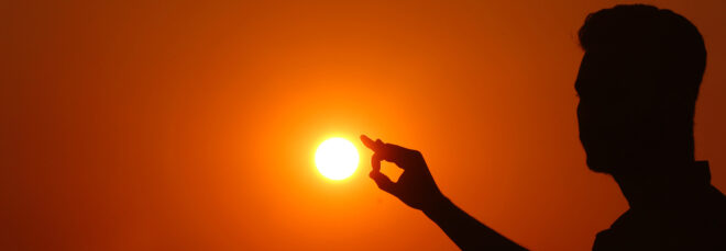 A silhouette of a person touching the sun