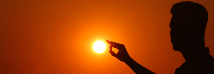 A silhouette of a person touching the sun