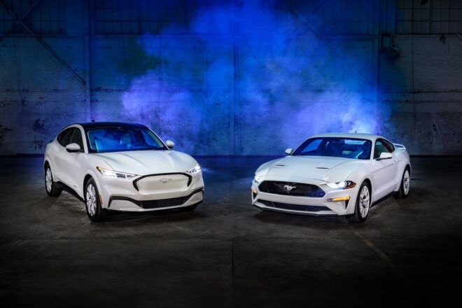 Two white Mustang EV facing each other with a blue light behind it