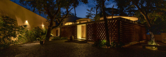 The Cloud House lit up at night peaks lights through the slits