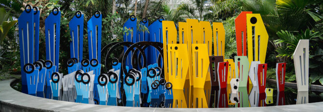 A row of flat sculptures with one side filled with blue ones and the other side yellow and orange and red
