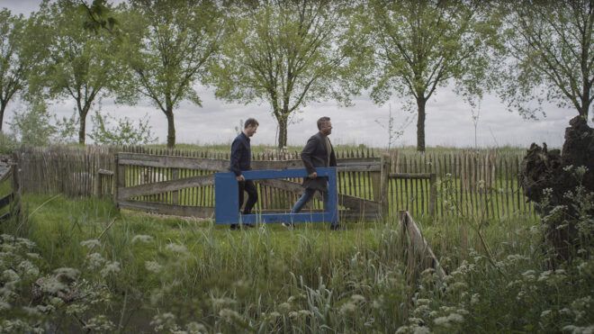 Two men carrying a wooden door to be reused in the project.