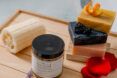 A set of Rustic Elements bar soap next to a natural loofah on a cutting board