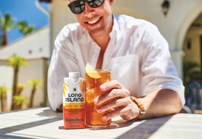 A man holding a brown alcohol in a cup