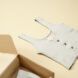 A white tank top laid next to a cardboard box on a cream floor