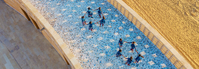 The roof has two groups of girls forming a circle with their hands held together