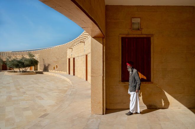 A person standing at a doorway of the curved structure