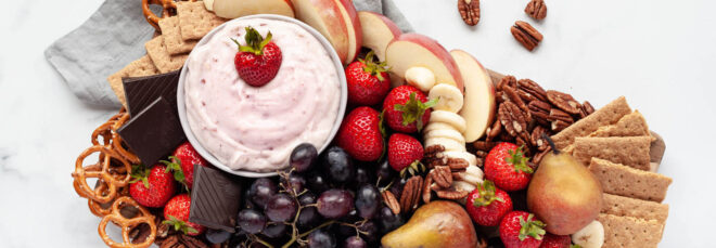 A cutting board full of fruits and snacks with Perfect Day cream cheese