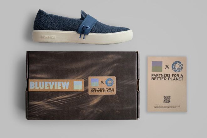 A blue sneakers laying flat against its box and a little information card beside it
