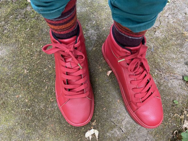The feet of someone wearing a pair of red sneakers