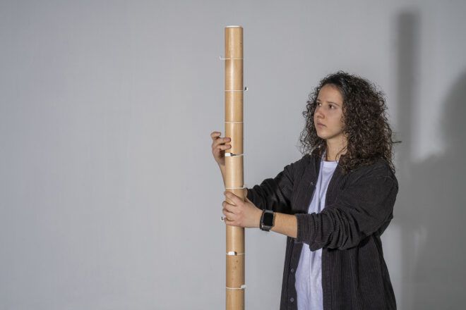 A woman holding a wooden pole coat rack in her hands