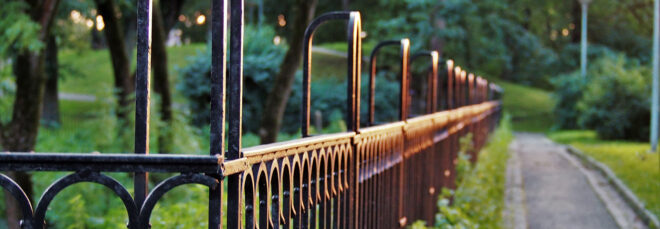 Black metal fencing in a park near a concrete walking path