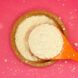 A white grain powder in a wooden bowl lifted by a wooden spoon