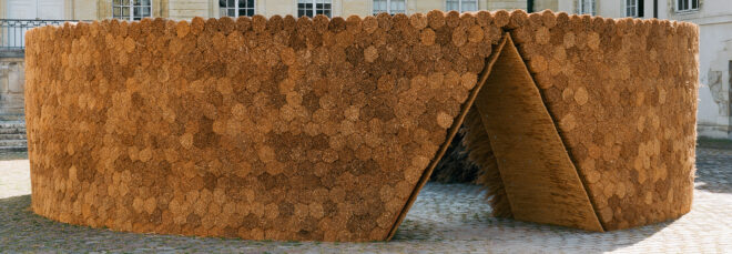 A circular wooden installation with a triangle walk through doorway
