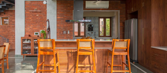 An island with wooden stools and a ceiling vent hanging over it