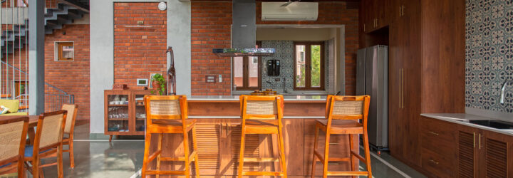 An island with wooden stools and a ceiling vent hanging over it