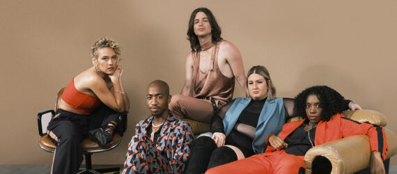 Five people posing and lounging in and around a sofa against a brown backdrop