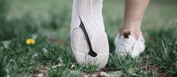 White soles of a sneaker pointed on a grass