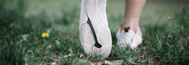 White soles of a sneaker pointed on a grass