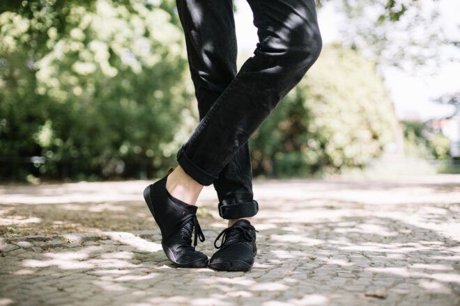 Black pants leading to black sneakers of the leg of a person posing on the ground