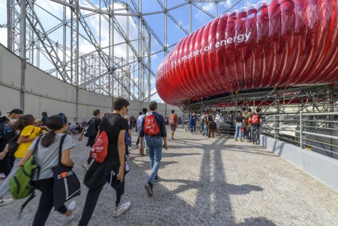 A group of people walking toward an inflatable round red object