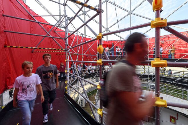 People walking along a ramp with an enclosed area with metal bars