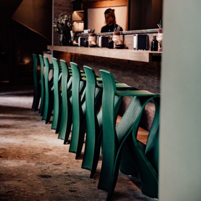 Eight green curvy barstools lined up at a bar