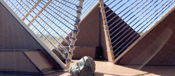 Interior of Vergence Pavilion. Parts of the interior are in shade while the sun casts interlacing grid pattern on the deck below from the jute rope canopy