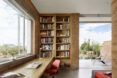 A workspace with an open window and an open doorway with a bookshelf that lines one wall