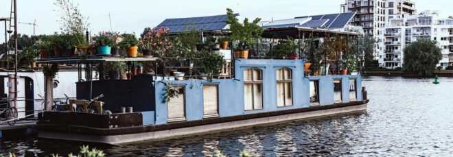 A houseboat with plants and tall glass windows