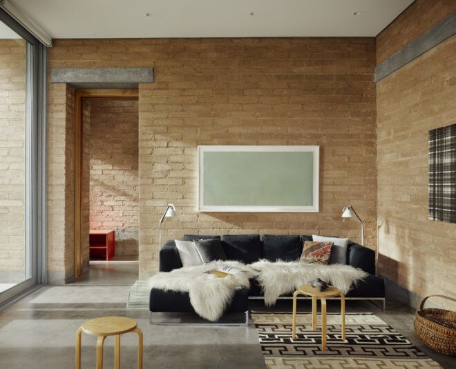 A living room area with a black sofa with a throw blanket over it