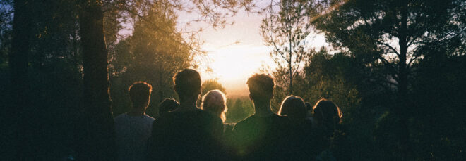People in the woods looking at the sunrise