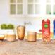 A tabletop of five glasses of coffees, espressos and at the far left are two coffee creamers from Nutpods