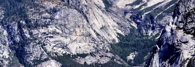 Mountains covered in snow leading down to a valley of forest