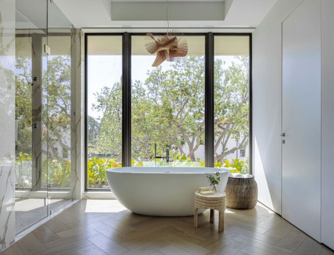 Natural light from tall windows in front of bathtub