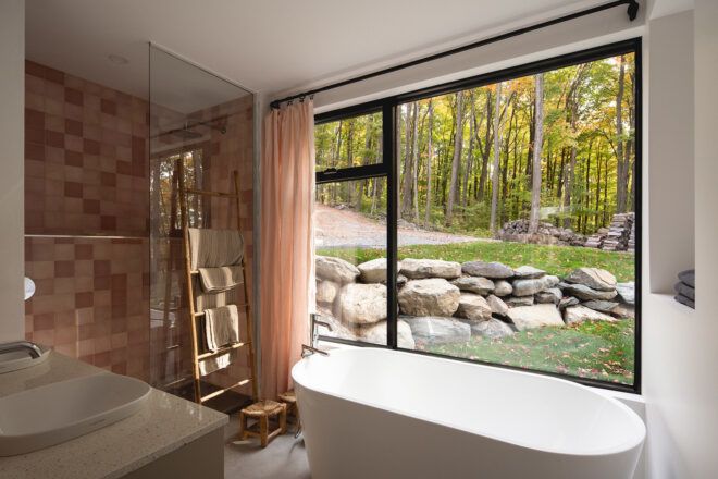 A bathtub and standing shower facing an open window